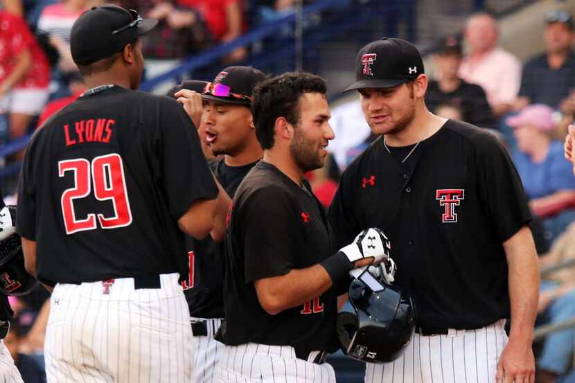 Texas Tech pitcher Matt Withrow, far right, congratulates Eric Gutierrez as he scores during...