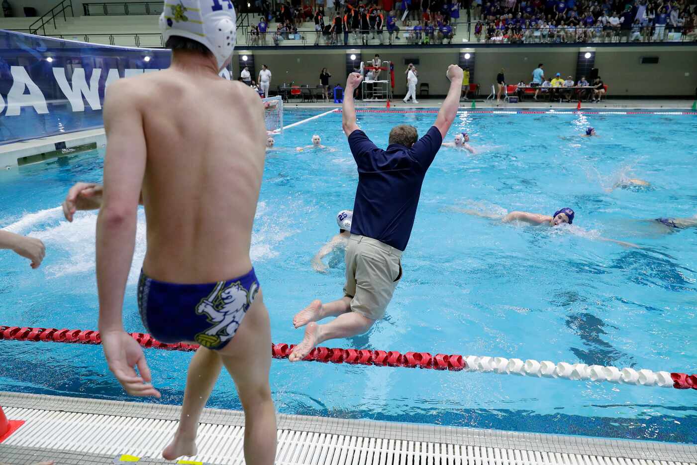 St. MarkÕs assistant coach Spencer Dornin, center, jumps into the pool with his players...