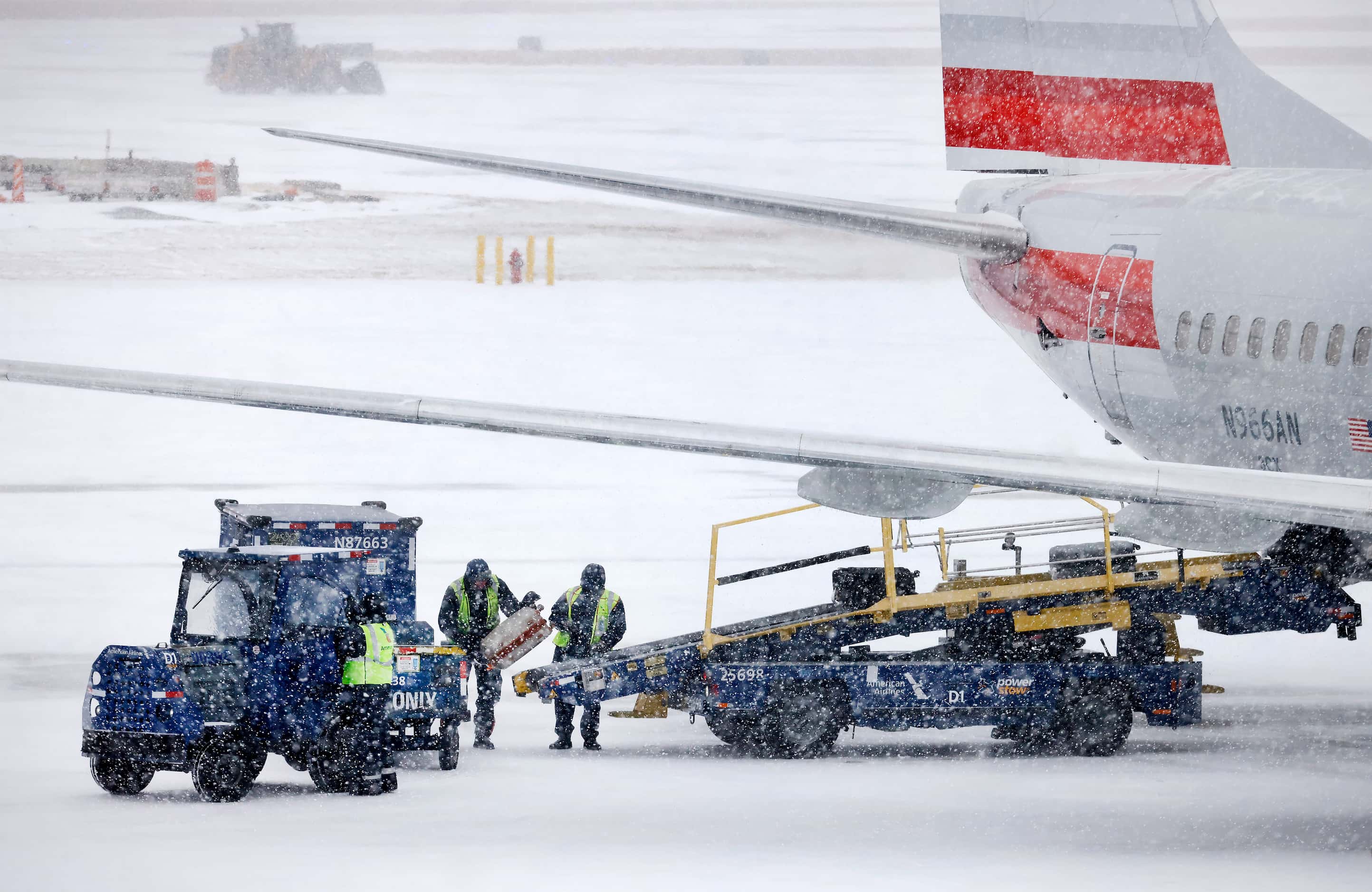 With sleet turning to snow, American Airlines baggage handlers load an aircraft at DFW...