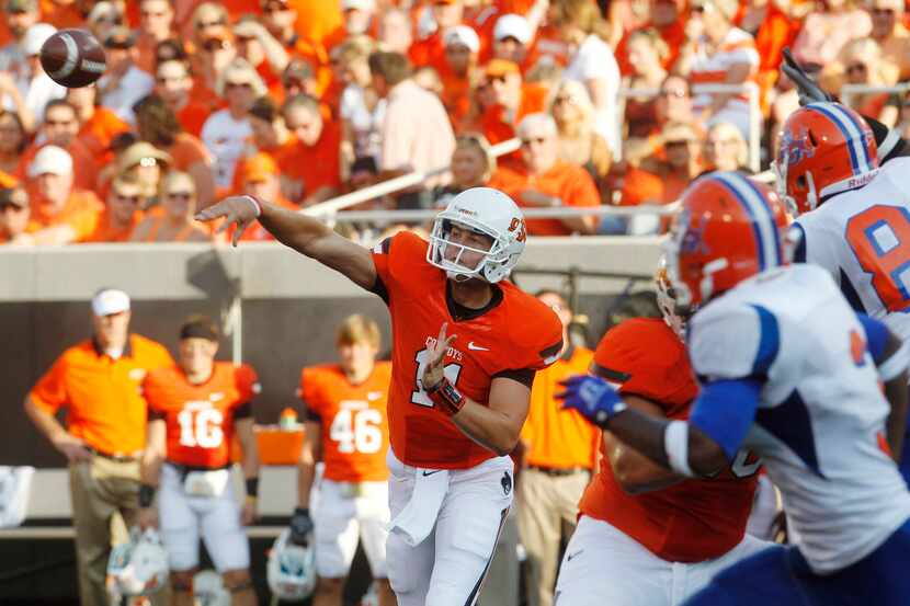 Oklahoma State quarterback Wes Lunt, left, passes under pressure from Savannah State in the...