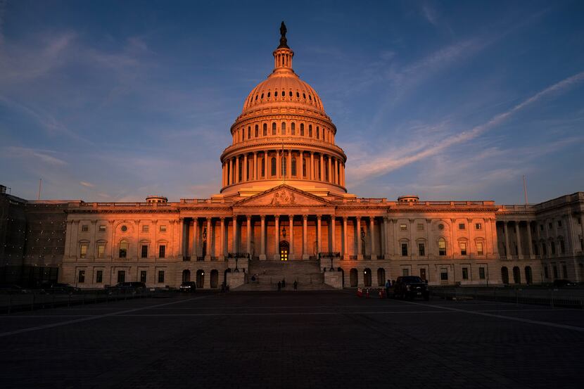The rising sun divides the West Front of the U.S. Capitol in Washington, Wednesday morning,...