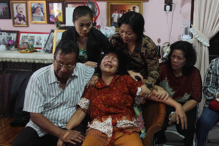 Risman Siregar (L) comforts his wife Erlina Panjaitan (C), parents of Firman Chandra...