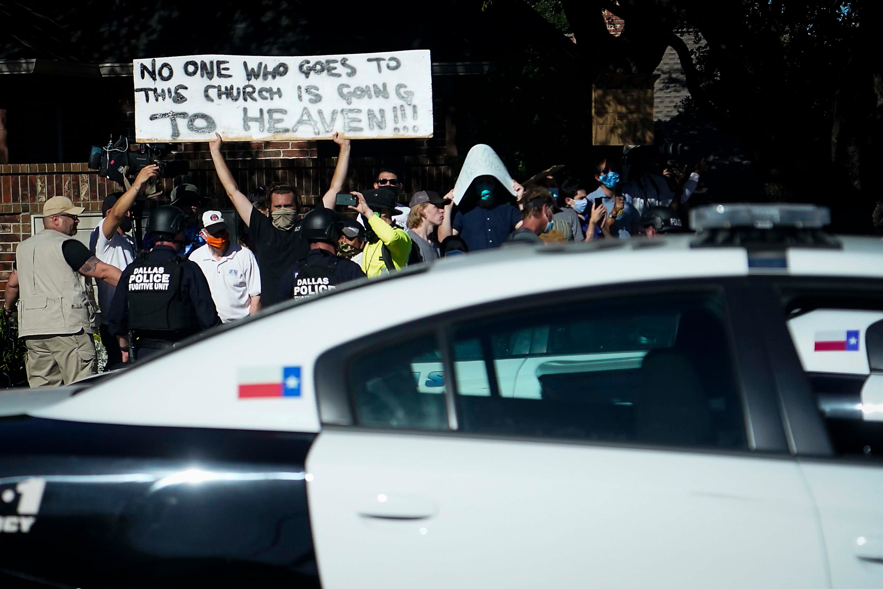 Protesters hold signs as President Donald TrumpÕs motorcade departs a roundtable...