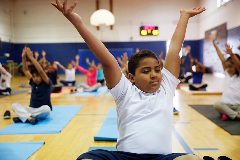 Tommie Reed, a fourth-grader in DISD's after-school program, does a yoga pose with others...