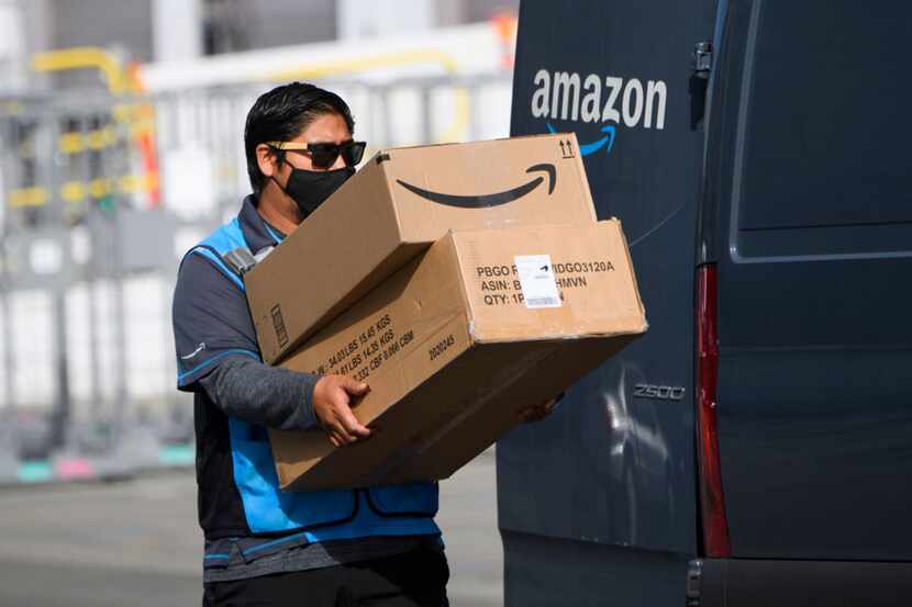 An Amazon.com Inc. delivery driver carries boxes into a van outside a distribution facility...