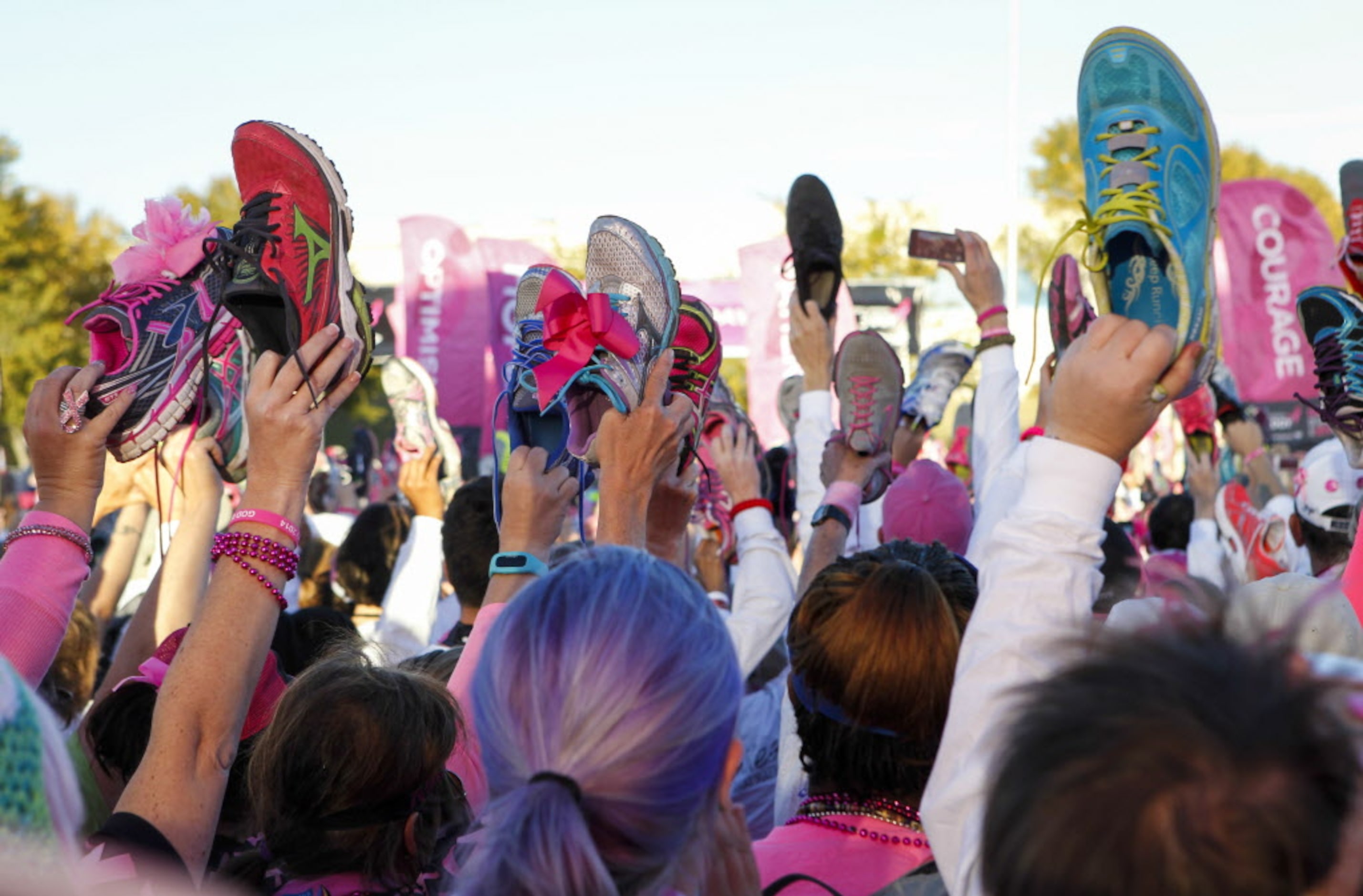 Walkers hold up their shoes in a salute to breast cancer survivors during the closing...