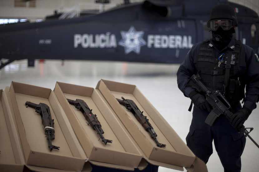 A policeman stands guard as some of the weapons seized from two members of the Zetas drug...