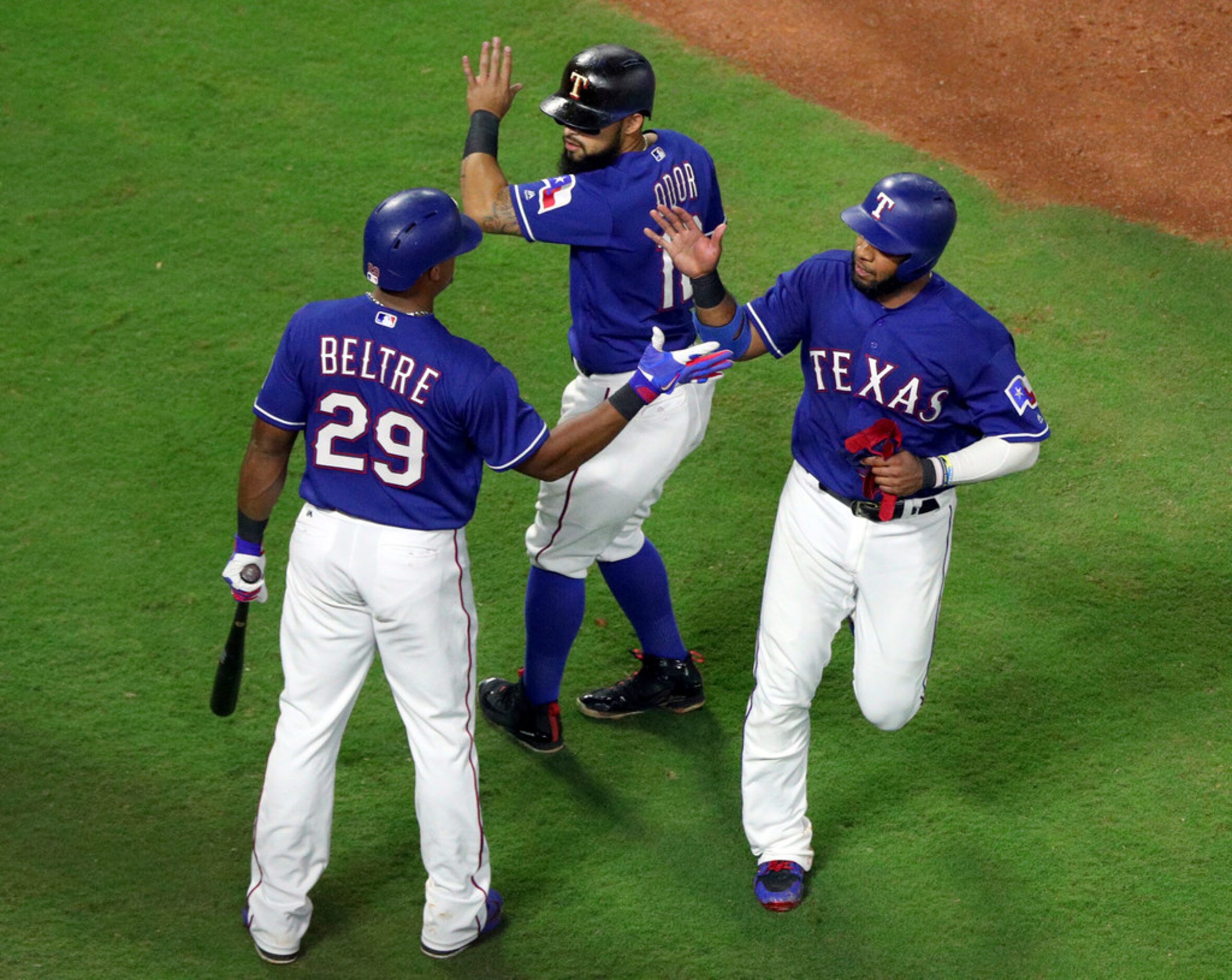 Texas Rangers' Adrian Beltre (29) greets Rougned Odor (12) and Elvis Andrus (1) who scored...