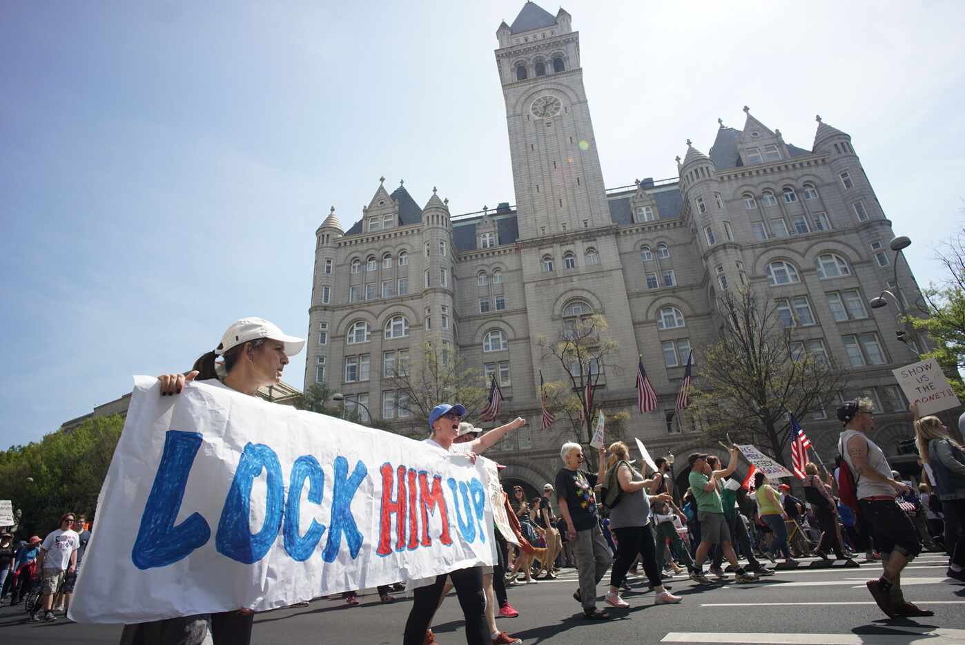 Protestors walk by the Trump hotel during the  "Tax March" to call on U.S. President Donald...