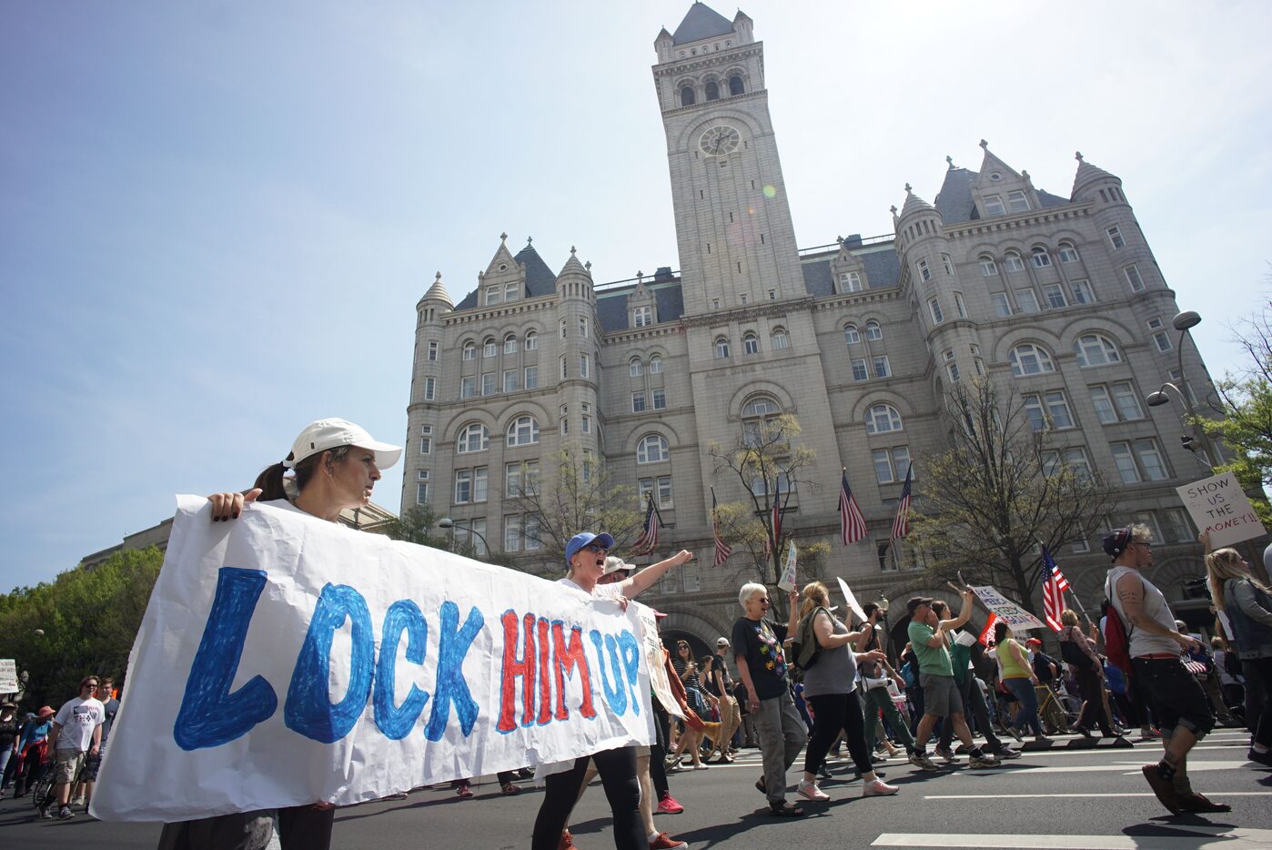 Protestors walk by the Trump hotel during the  "Tax March" to call on U.S. President Donald...