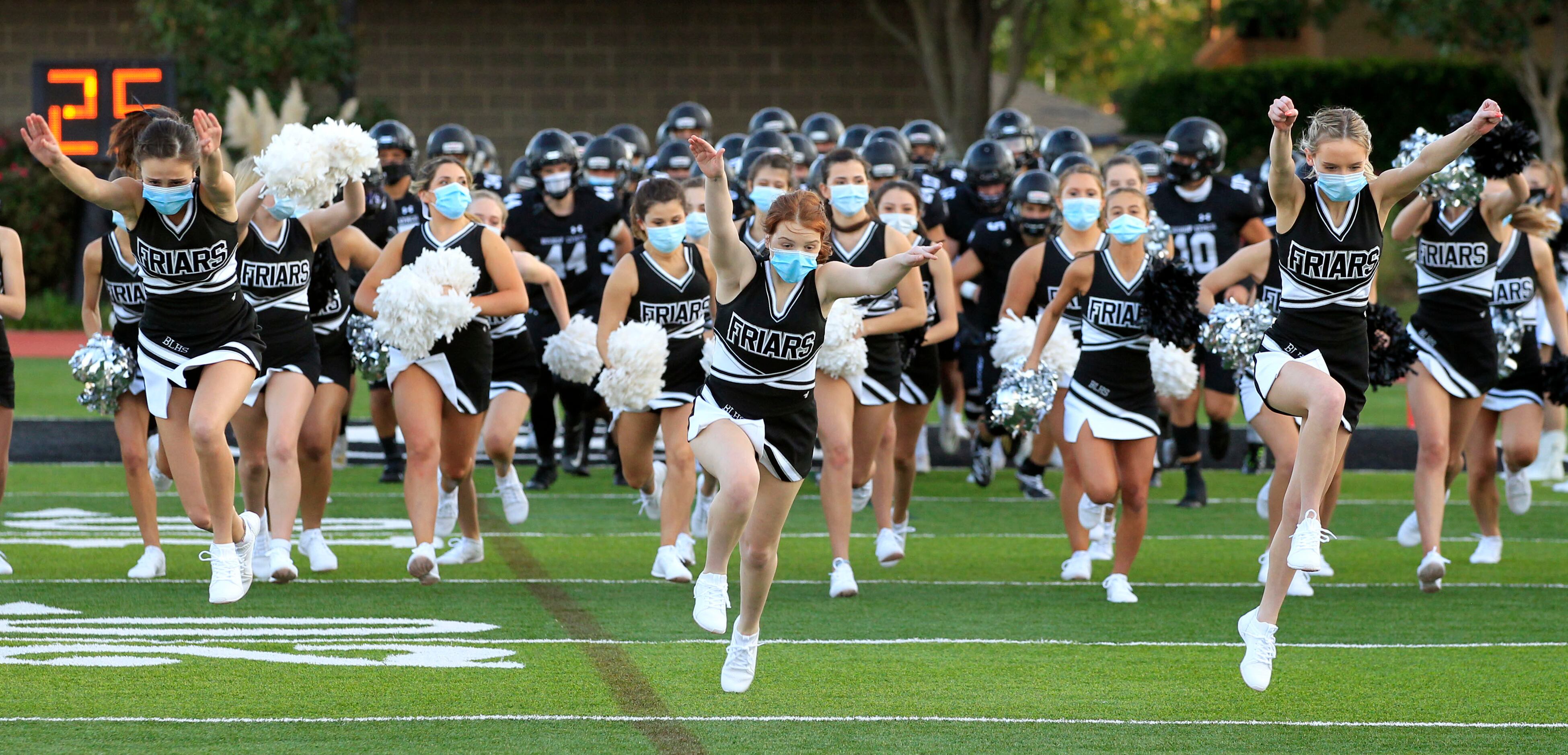 The Bishop Lynch team and cheerleaders run onto the field before the start of the first half...