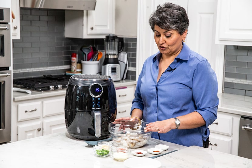 Urvashi Pitre prepares tandoori shrimp in an air fryer at her home in Keller.