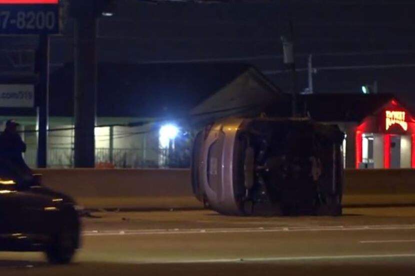 A car lies on its side after it and a Dallas police squad car crashed into each other...