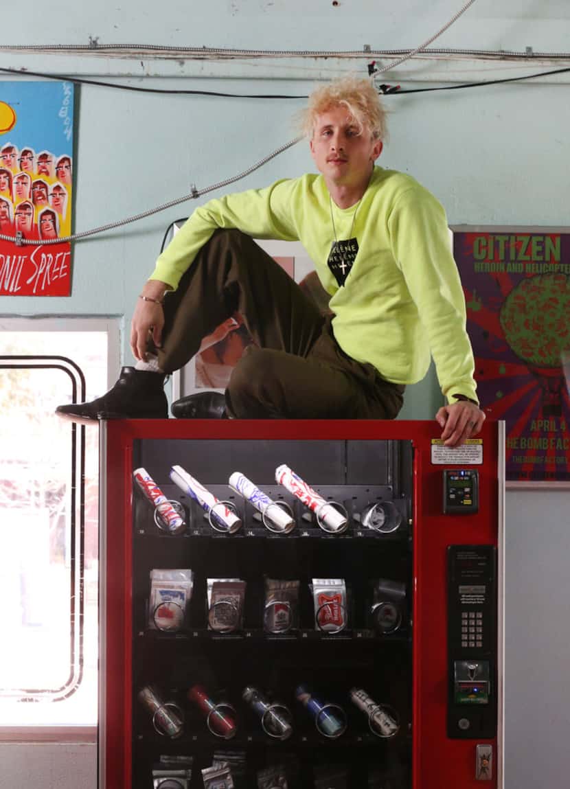 Artist Matthew Brinston poses for a photograph atop his art vending machine at Good Records...