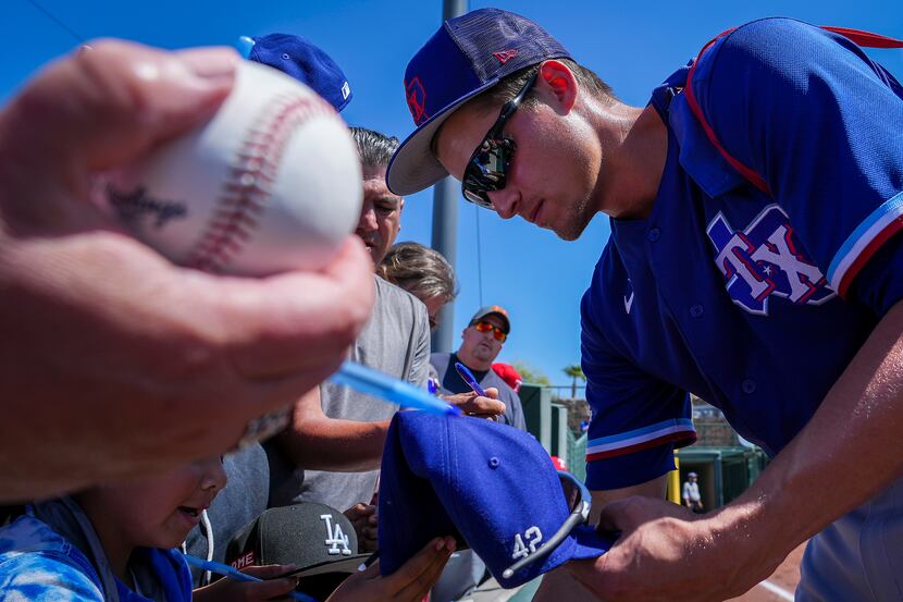 Texas Rangers shortstop Corey Seager signs autographs before a spring training game against...