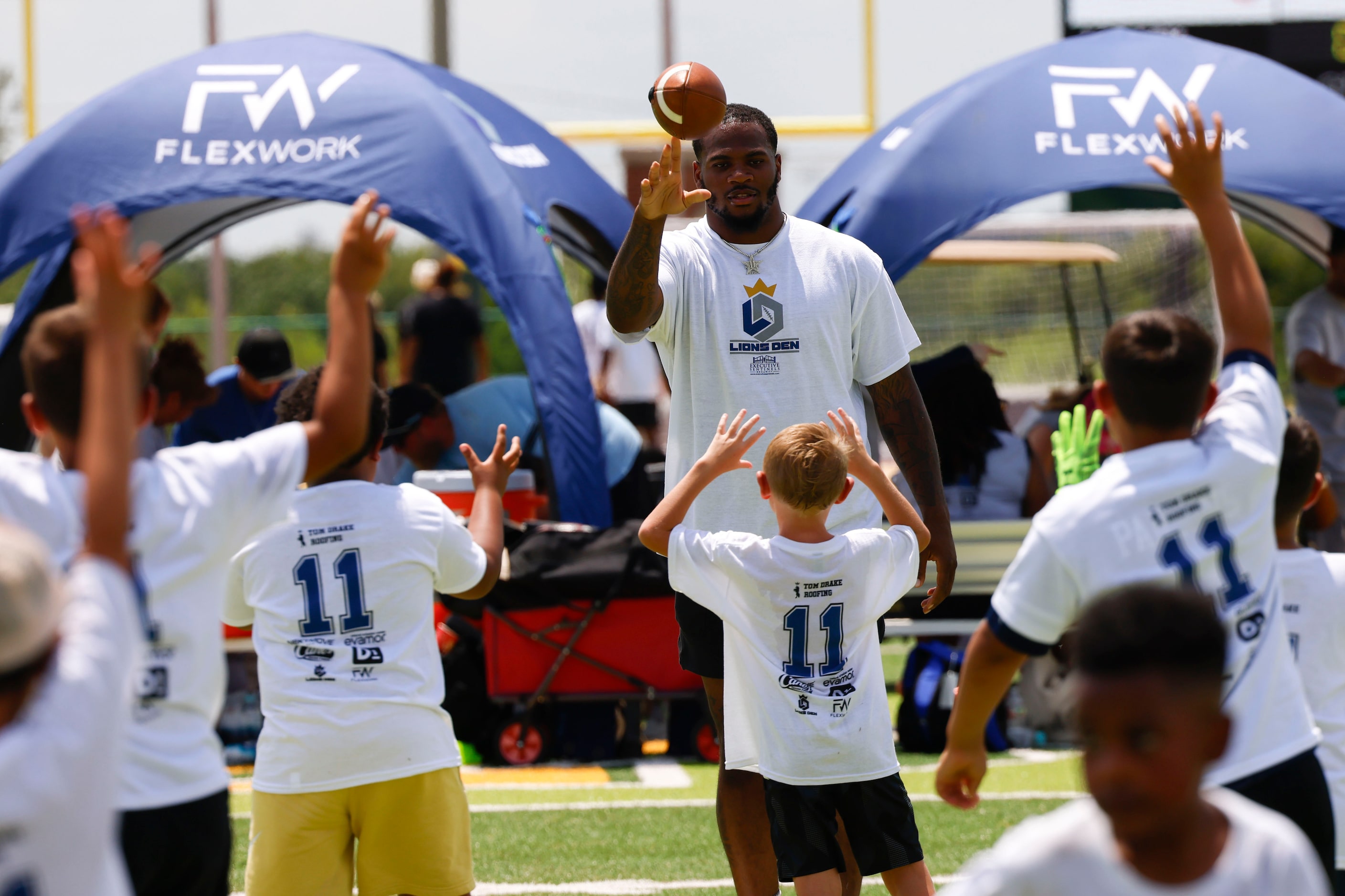 Dallas Cowboys linebacker Micah Parsons looks to throw the ball as he interacts with young...