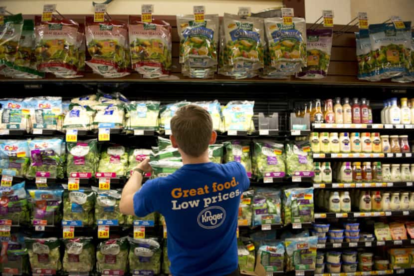 A Kroger employee stocks salad mixes in the produce department of a Peoria, Ill., store....