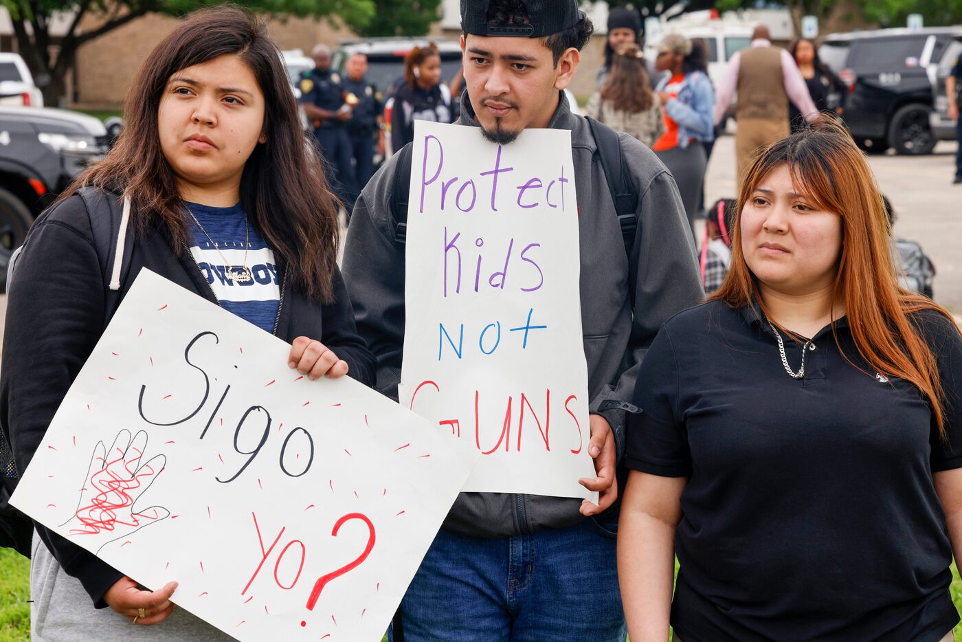 Melany Lopez, 17 (from left), Christopher Leon, 17, and Steisy Montero, 16, hold signs...