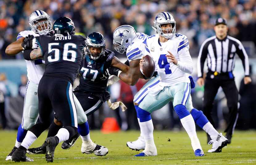 Dallas Cowboys quarterback Dak Prescott (4) looks for a receiver as he bounces around in the...