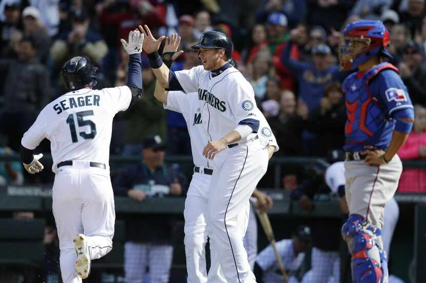 Seattle Mariners' Kyle Seager (15) is greeted by teammates Justin Smoak, center, and Dustin...