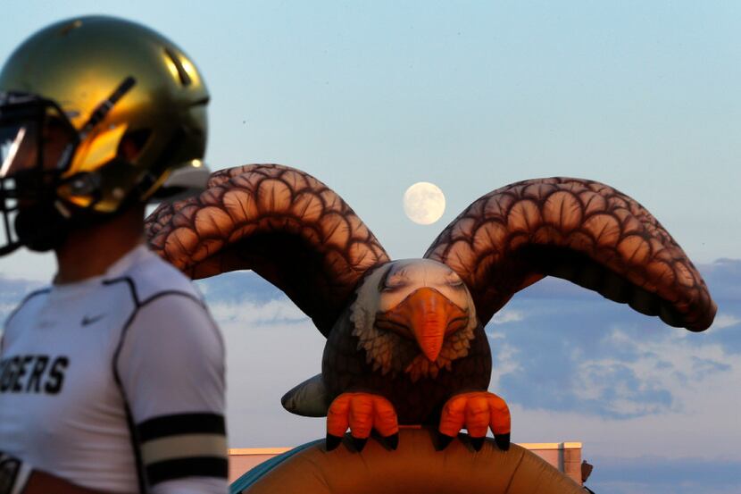 A nearly full moon rises over the DeSoto Eagles inflatable mascot as an Irving football...