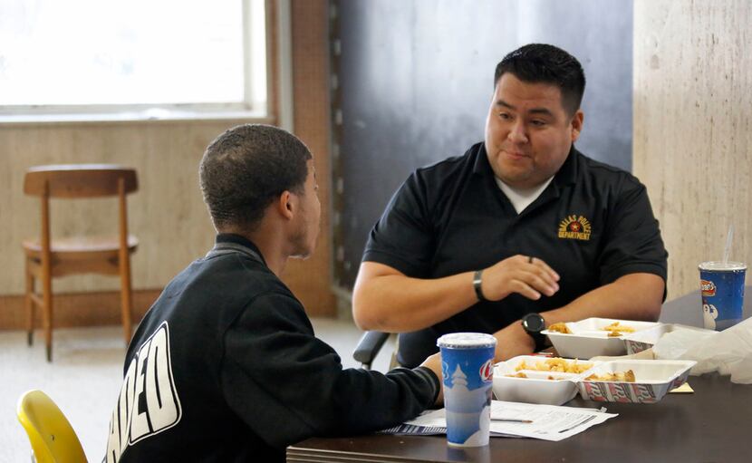 Dallas Police Officer Victor Guardiola (right) talks with Carter High School student Sedric...