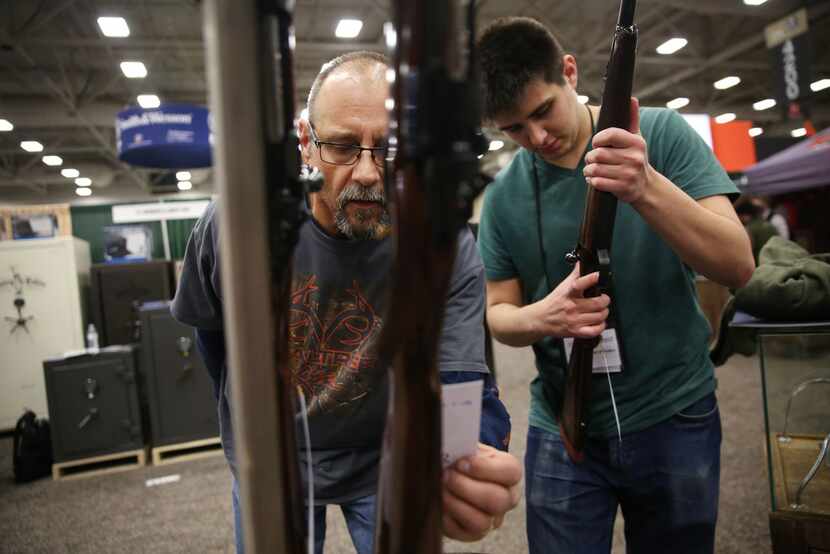 Lenny Perko and his son Lucas Perko look at Rigby firearms during the Dallas Safari Club...