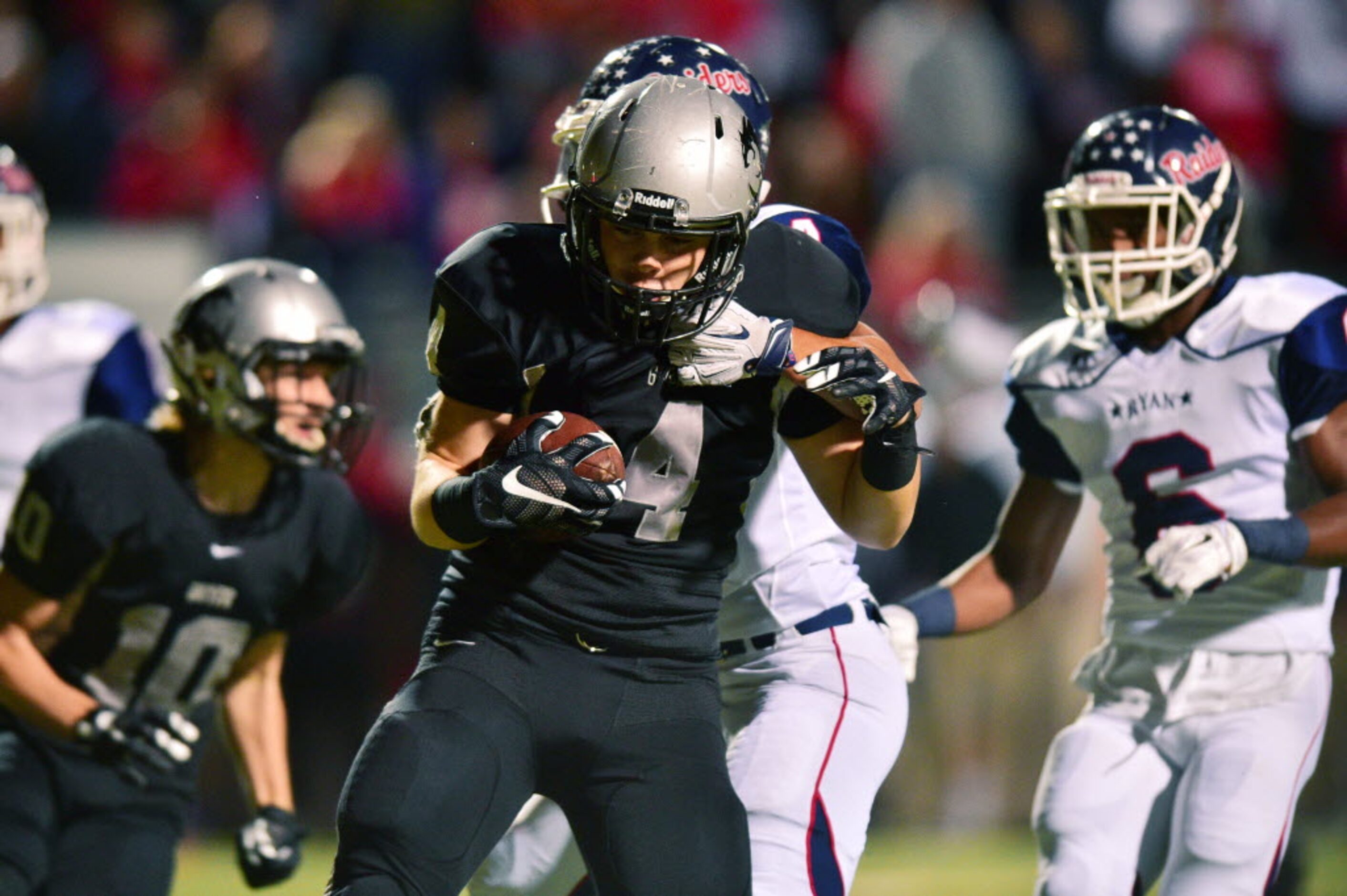 Guyer senior running back Austin Luna (4) fights off a tackle from Ryan senior defensive...