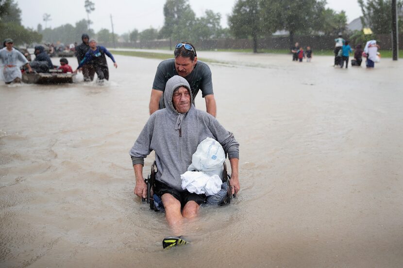 People make their way out of a flooded neighborhood after it was inundated with rain water,...