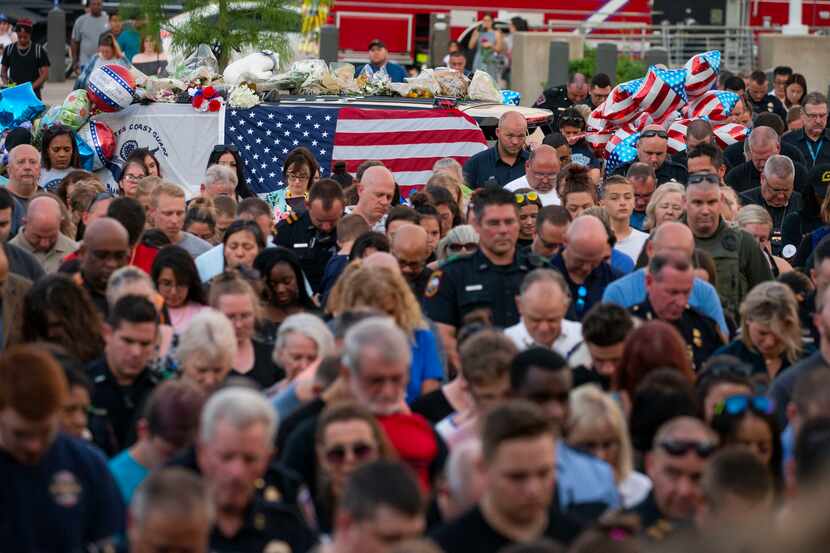 Attendees bow their heads during a vigil Sunday for Grand Prairie police Officer Albert...