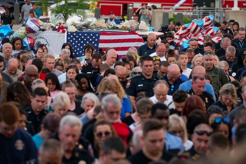 Attendees bow their heads during a vigil Sunday for Grand Prairie police Officer Albert...