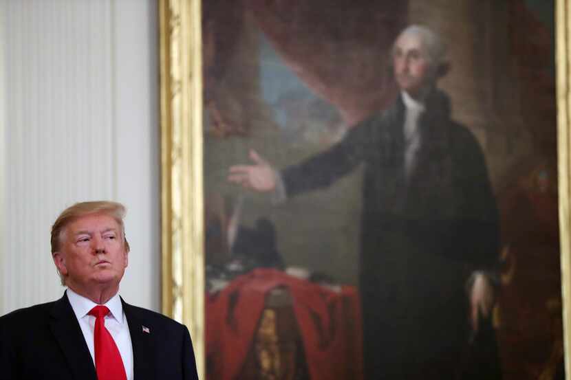 President Donald Trump stands near a portrait of George Washington at a Wounded Warrior...
