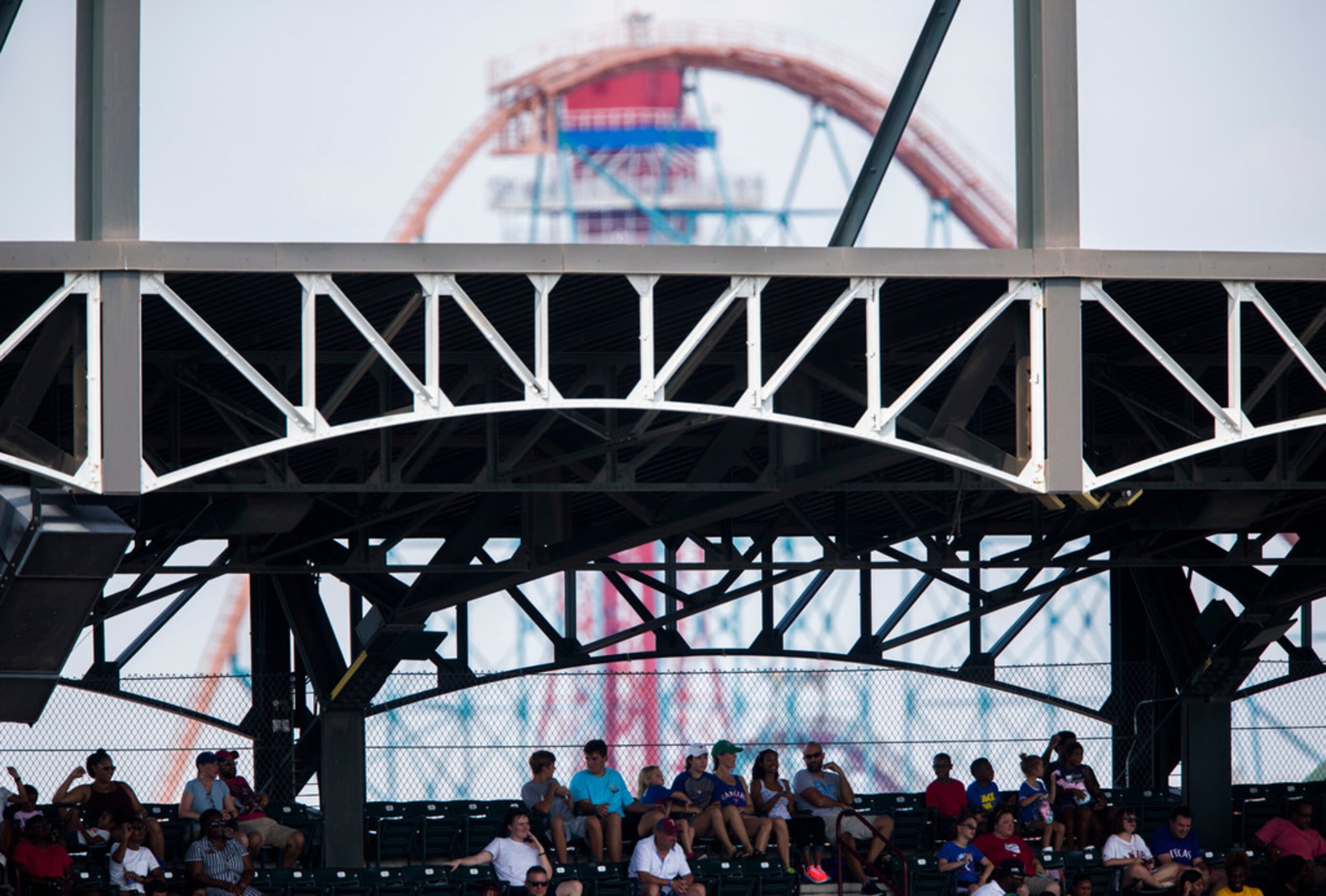 A roller coaster at Six Flags Over Texas theme park is seen behind fans on the upper deck of...