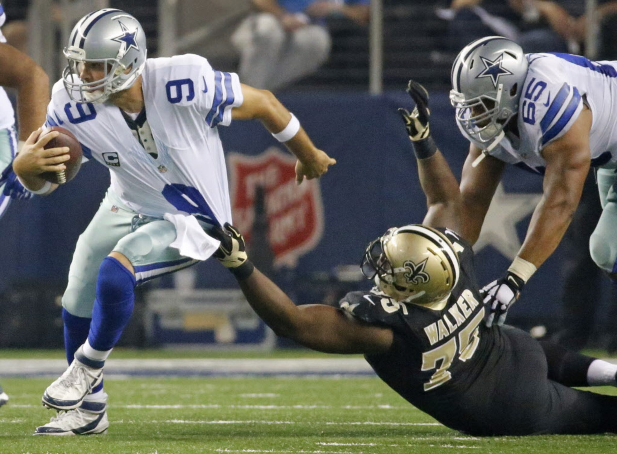 Dallas Cowboys quarterback Tony Romo (9) eludes the grasp of New Orleans Saints defensive...