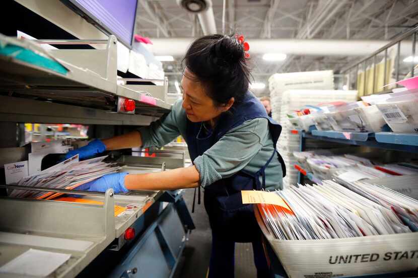 Clerk Petty Chow grabs a handful of canceled mail after it had been sorted in the Advanced...