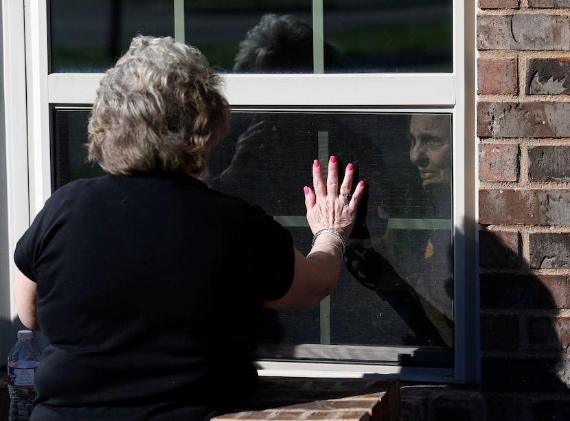 Cindy Goleman waves goodbye to her mother Peggy White from opposites sides of the window at...