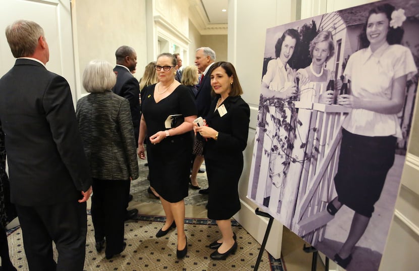 Attendees walk past a photo of Ruth Altshuler, at right in the black-and-white photograph,...
