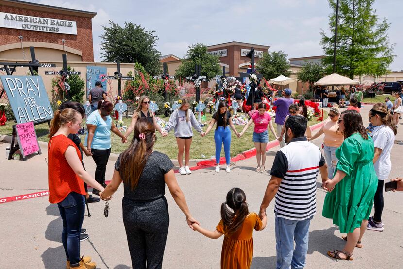 People held hands as they prayed at a memorial for victims of the Allen Premium Outlets mass...
