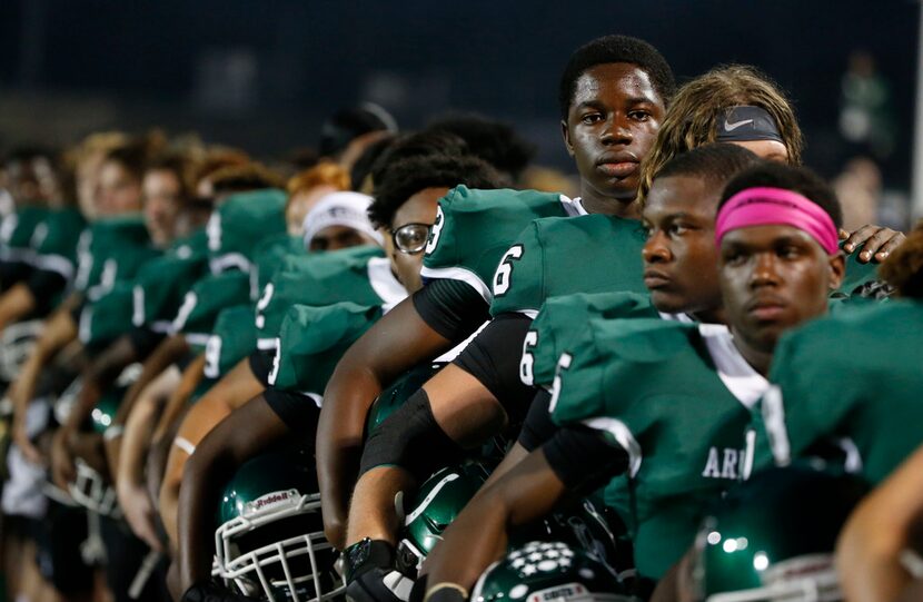 Arlington defensive lineman Victor Ezeagba, center, an exchange student from Africa,  lines...