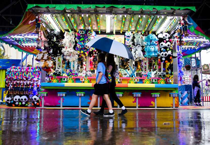 Fairgoers walk through the rain in the midway at the State Fair of Texas on Tuesday, October...
