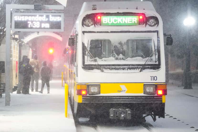 Usuarios esperan bajo la nieve para abordar uno de los autobuses de DART en el área...