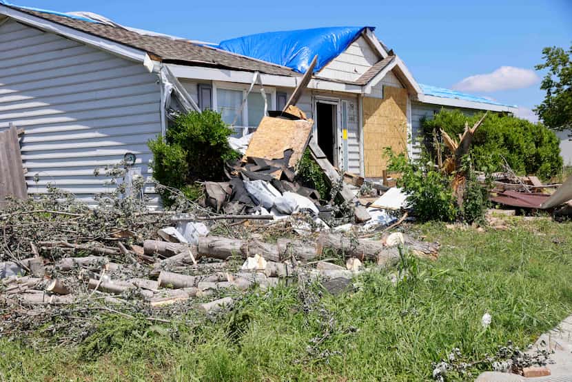 Debris from an EF2 tornado is seen outside the tarp-covered home of David Vickery in Frf...