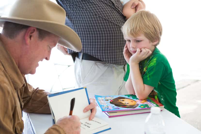 Craig Johnson autographs a book for Eliot Donmoyer, 5, of Austin at the Texas Book Festival...