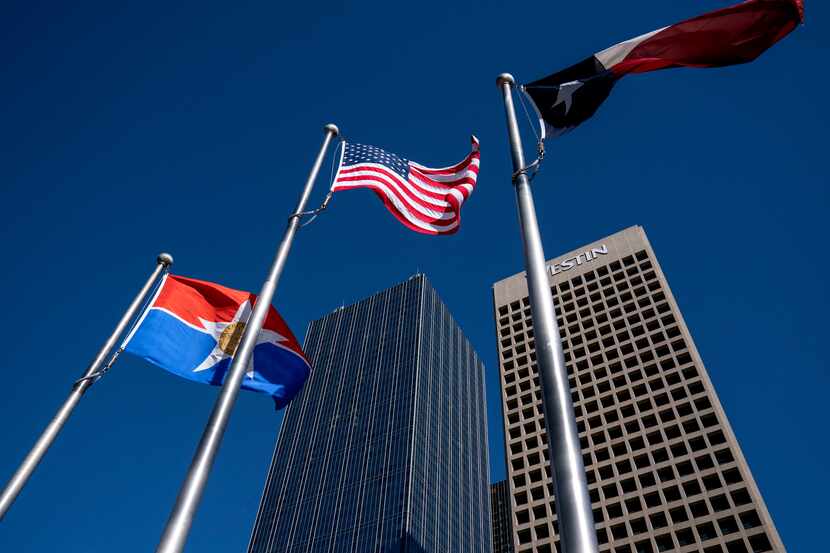 The flags of the City of Dallas, United States and Texas fly in front of Renaissance Tower...