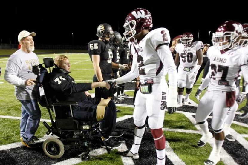 
Austin, in wheelchair, who was injured in a car accident on Sept. 30, shakes hands with...