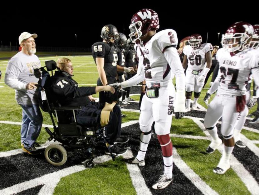 
Austin, in wheelchair, who was injured in a car accident on Sept. 30, shakes hands with...