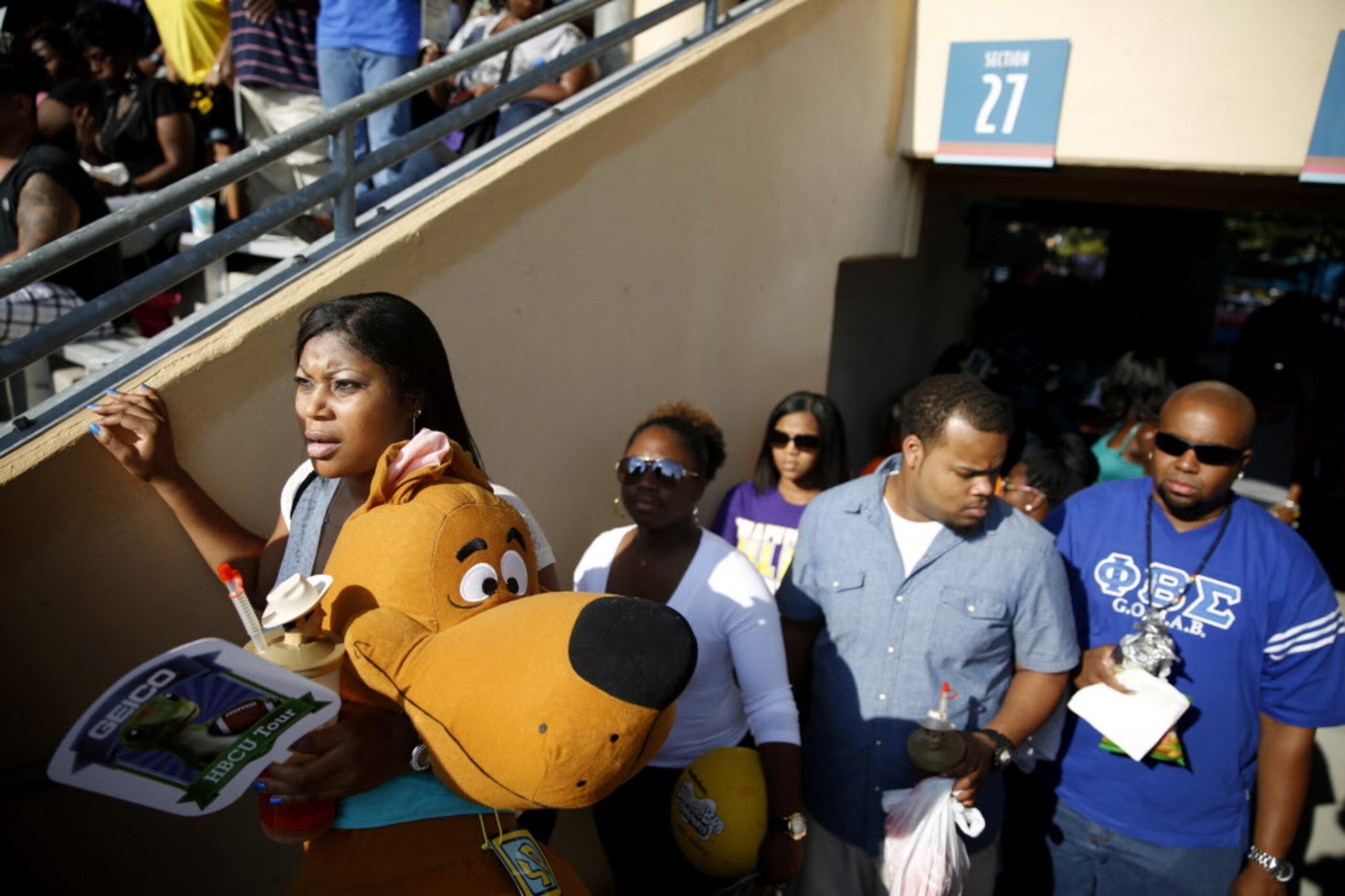 Emell Eley (left), of Dallas, looks for her seat while carrying a Scooby Doo stuffed toy...