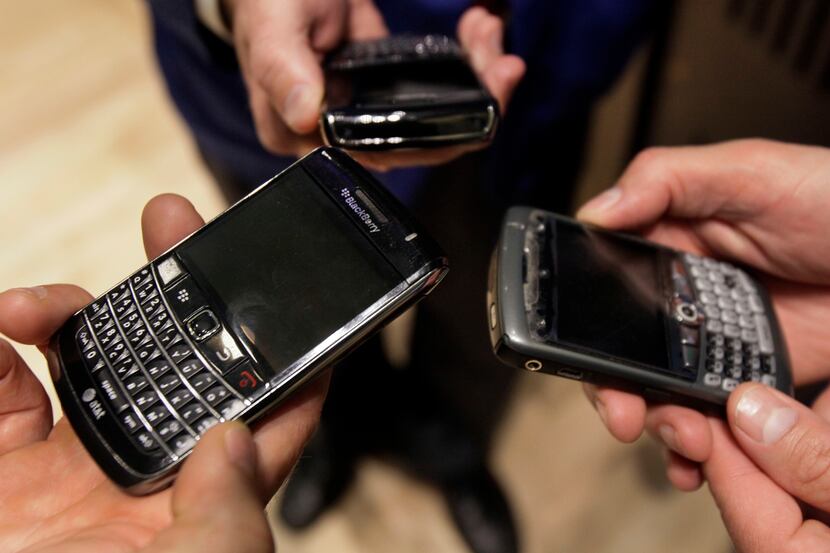 Three people on the floor of the New York Stock Exchange display their Blackberry...