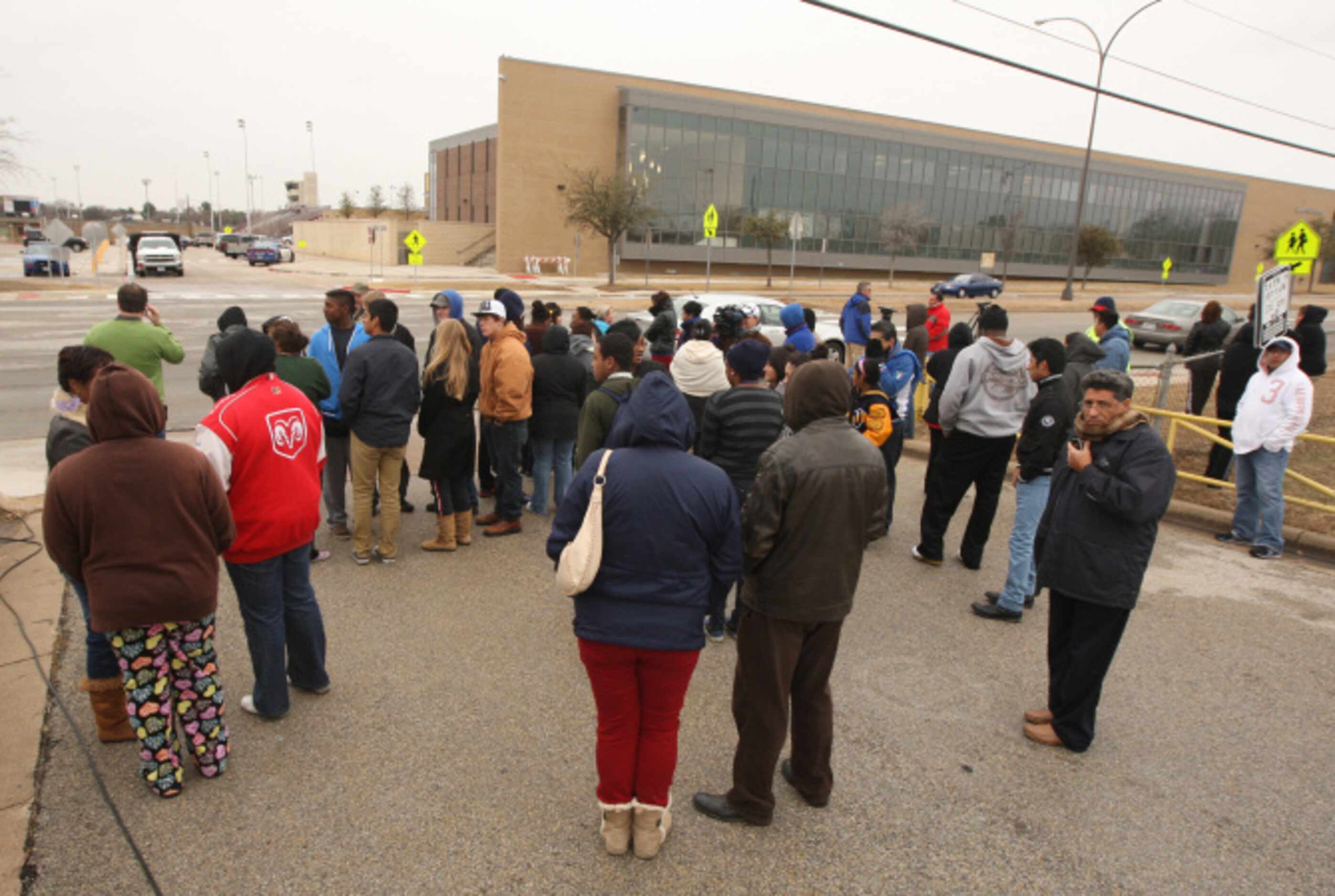 Parents wait across the street during a lockdown at Arlington Lamar High School due to a...