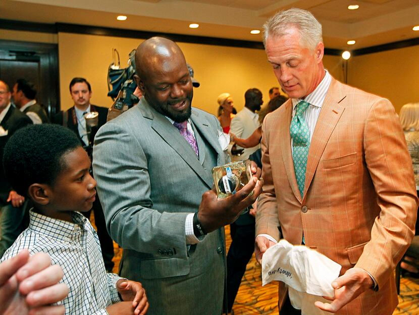 Emmitt Smith (center) stands with his son, Emmitt IV, as he displays a gift bottle of...
